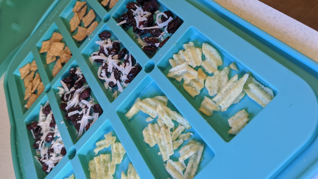 Making homemade chocolate bars. A silicone bar mold full of add INS like potato chips, cinnamon cereal, and craisin coconut. 