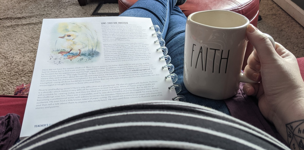 A woman with a slightly pregnant belly with a "faith" coffee mug and homeschool curriculum resting on their lap.