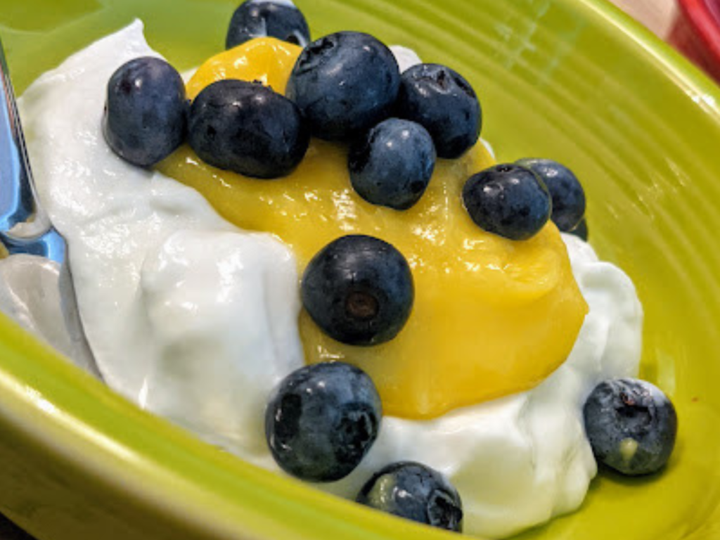 A bowl layered with yogurt, lemon curd and fresh blueberries. 