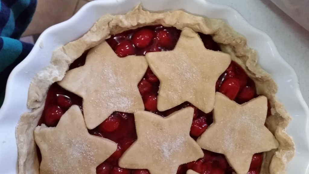 An unbaked homemade cherry pie with cutout pie crust stars sitting on top. 